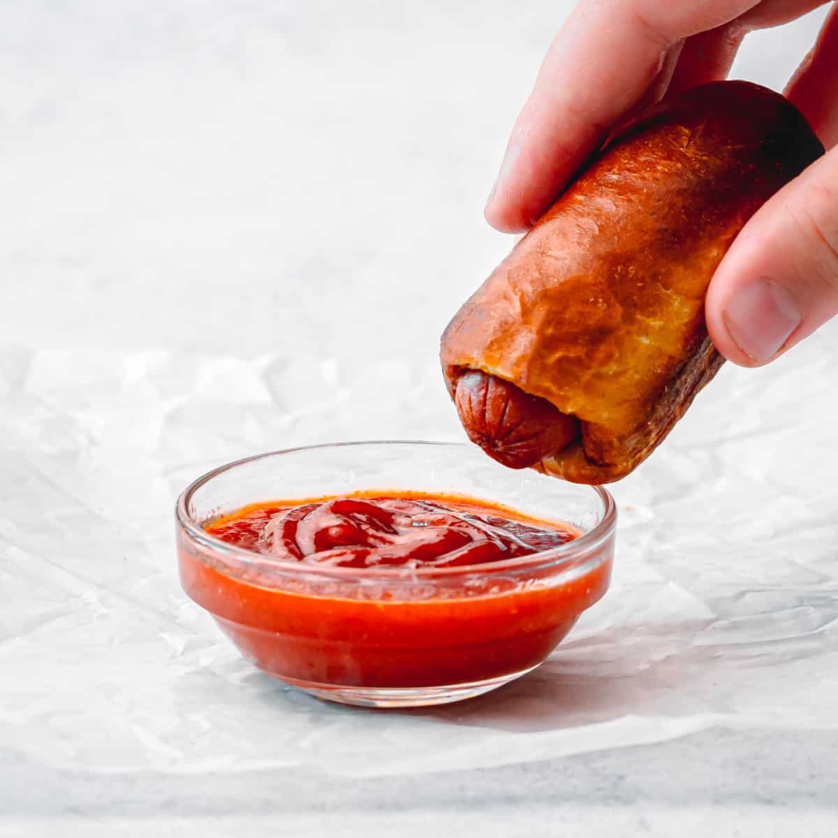 a little hand with a pretzel dog and ketchup. 